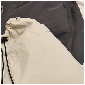 Detailed close-up of beige nylon fabric with black adjustable drawstring and plastic toggle