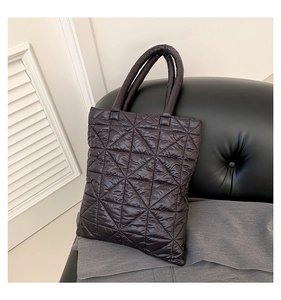 Macro shot of geometric triangular quilted stitching on a black puffy nylon tote bag