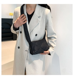 Close-up van zwarte gewatteerde nylon crossbodytas met brede schouderband op model