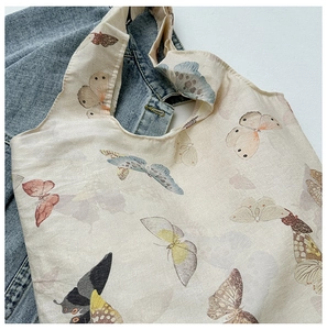 Detail of a minimalist canvas tote bag with colorful butterfly prints on white fabric