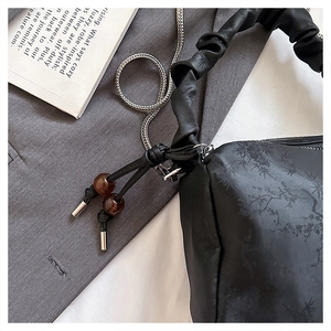 Detailed shot of pleated black shoulder bag featuring bamboo leaf jacquard and resin beads