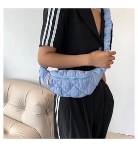 Detailed view of light blue quilted crossbody bag with stylish pleated strap and gold zipper