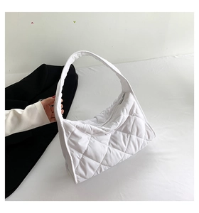 Detalle del bolso de hombro acolchado blanco con diseño de rombos y cremallera plateada