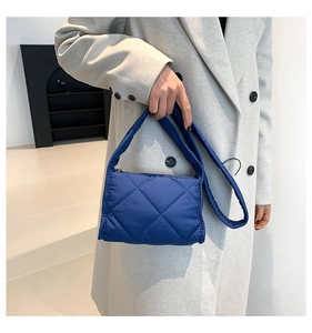 Detail van donkerblauwe gewatteerde crossbodytas met ruitstiksel en zachte textuur