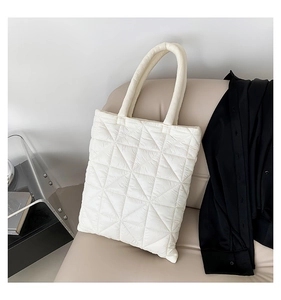 Close-up of white quilted tote bag with geometric stitching on a soft beige sofa