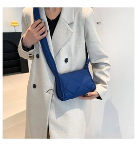 Detail van donkerblauwe gewatteerde crossbodytas met ruitjespatroon op een model
