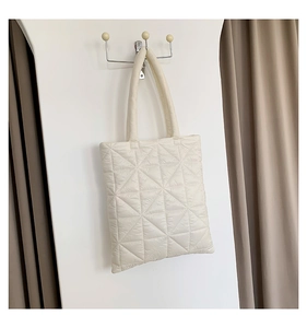 Detailed view of the soft triangle quilted texture and puffy fabric of the cream tote bag