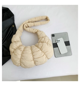 Beige crescent dumpling bag with pleated texture shown alongside tablet and phone
