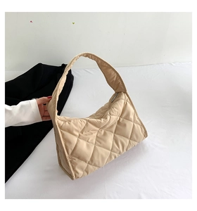 Primer plano del bolso tote acolchado beige con costuras de diamante y correa ancha