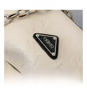 Detailed macro view of cream leather grain with silver chain and black triangle plaque