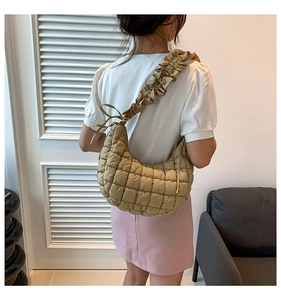 Close-up of khaki quilted dumpling bag featuring ruffled strap and bow details
