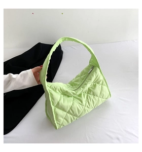 Detalle del bolso tote acolchado verde claro con diseño de rombos y cremallera plateada