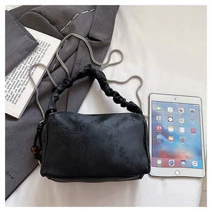 Detail of black pleated handbag with floral texture, chain strap and size reference