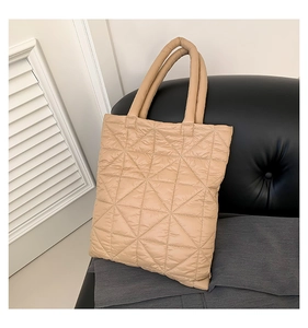 Close-up of beige quilted tote bag showing detailed triangle stitching and padded handles