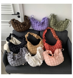 Quilted dumpling shoulder bags shown in nine different colors on a cozy gray fabric sofa