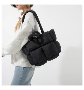 Close-up of black quilted puffer tote bag showing large square stitching and soft nylon texture