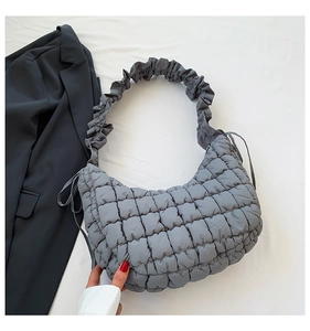 Detail of grey quilted dumpling bag featuring ruched strap and soft cloud texture