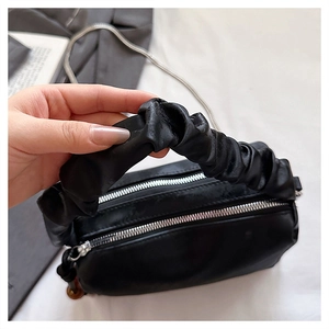 Detail view of the black pleated cloud handle and silver double zippers on the handbag