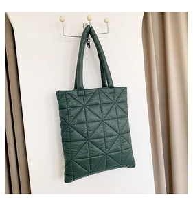 Close-up of dark green quilted tote bag with geometric triangle stitching detail