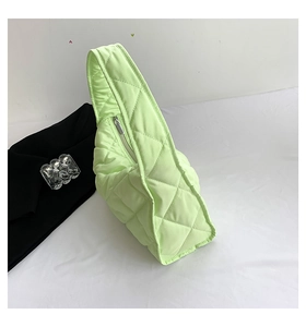 Detalle de bolso tote acolchado verde claro con costuras de rombos y cremallera