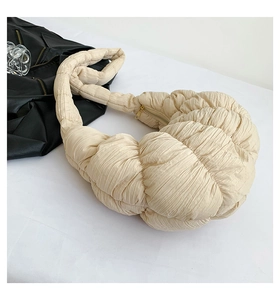 Detail of beige pleated cloud crossbody bag showing soft quilted texture and zipper