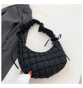 Detail of black quilted dumpling bag featuring a ruched strap and soft pleated texture