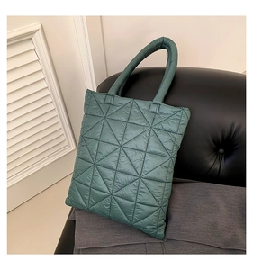 Detail of dark green quilted tote bag showing geometric triangle stitching and texture