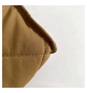 Détail de la couture en losanges sur un sac à bandoulière marron en tissu matelassé