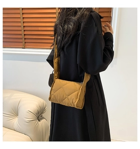 Detailweergave van een gewatteerde crossbodytas met brede riem en ritssluiting