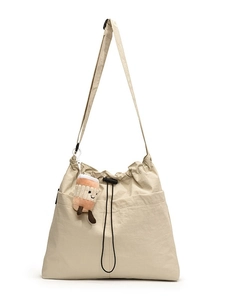Beige drawstring tote bag with plush coffee charm and adjustable shoulder strap