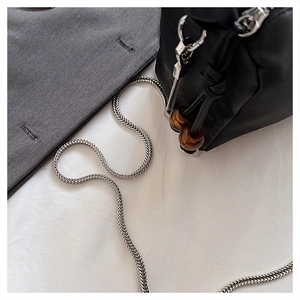 Detail of black pleated bucket bag featuring silver chain strap and amber decorative beads