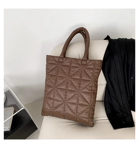 Detail view of brown quilted tote bag with triangle stitching on a white leather sofa