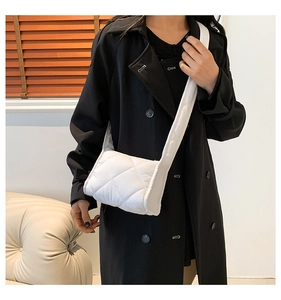 Detail van witte gewatteerde puffer schoudertas met ruitpatroon en brede comfortabele riem