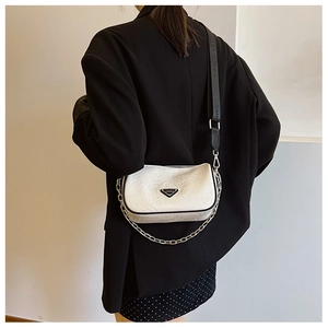Detail of white wrinkled leather pillow bag with a wide nylon strap and metal logo