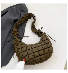 Detail of dark olive quilted puff handbag featuring ruffled straps and ruched texture