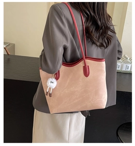 Detail of contrast tote bag in beige suede and red leather with plush charm