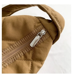 Détail du sac à bandoulière marron matelassé avec fermeture éclair métallique argentée