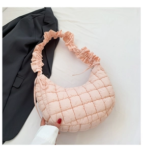 Detail of light pink quilted hobo bag featuring ruffled strap and soft nylon texture