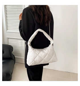 Détail d'un sac à bandoulière matelassé blanc porté au bras par un mannequin