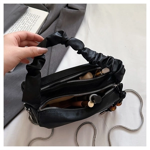 Close-up of double zipper compartments showing makeup storage in black pleated handbag