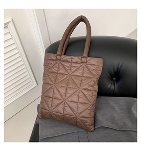 Detail of a brown quilted tote bag with triangle stitching on a black leather chair