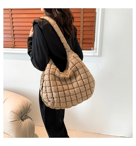 Detail of khaki quilted puffer shoulder bag showing texture and wide strap on model
