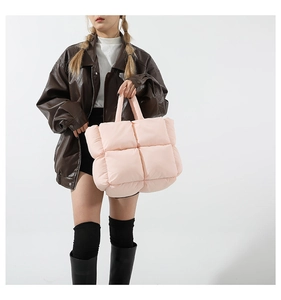 Detail of light pink quilted puffer tote bag showing soft padded texture and top handle