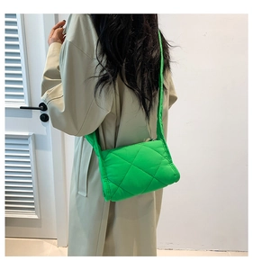 Detail van een groene gewatteerde crossbodytas met stijlvol ruitpatroon en textuur