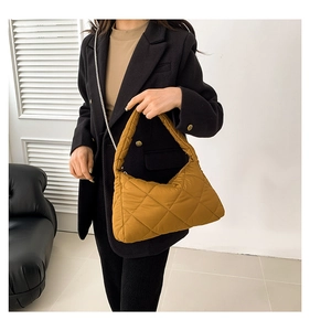 Détail d'un sac hobo matelassé jaune moutarde porté par un mannequin dans un décor épuré