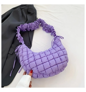 Detail of purple quilted dumpling bag with ruffled strap and soft plaid texture