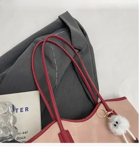 Detailed view of pink and red tote bag with plush charm, styled on a grey blazer