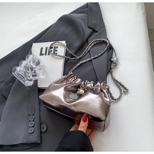 Detail of silver pleated cloud bag featuring pearl chain strap and metallic finish