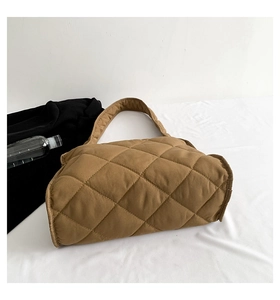Gros plan du sac à bandoulière matelassé marron avec surpiqûres losanges sur table
