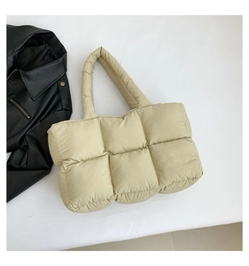 Detailansicht einer beigen gesteppten Puffer-Tasche mit großen Karos und weicher Textur